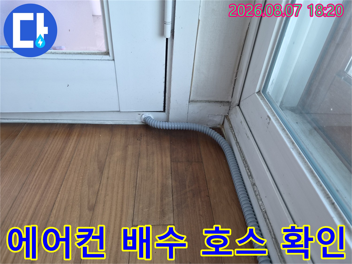 창틀 아래로 연결된-회색 에어컨 드레인 배수 호스 모습