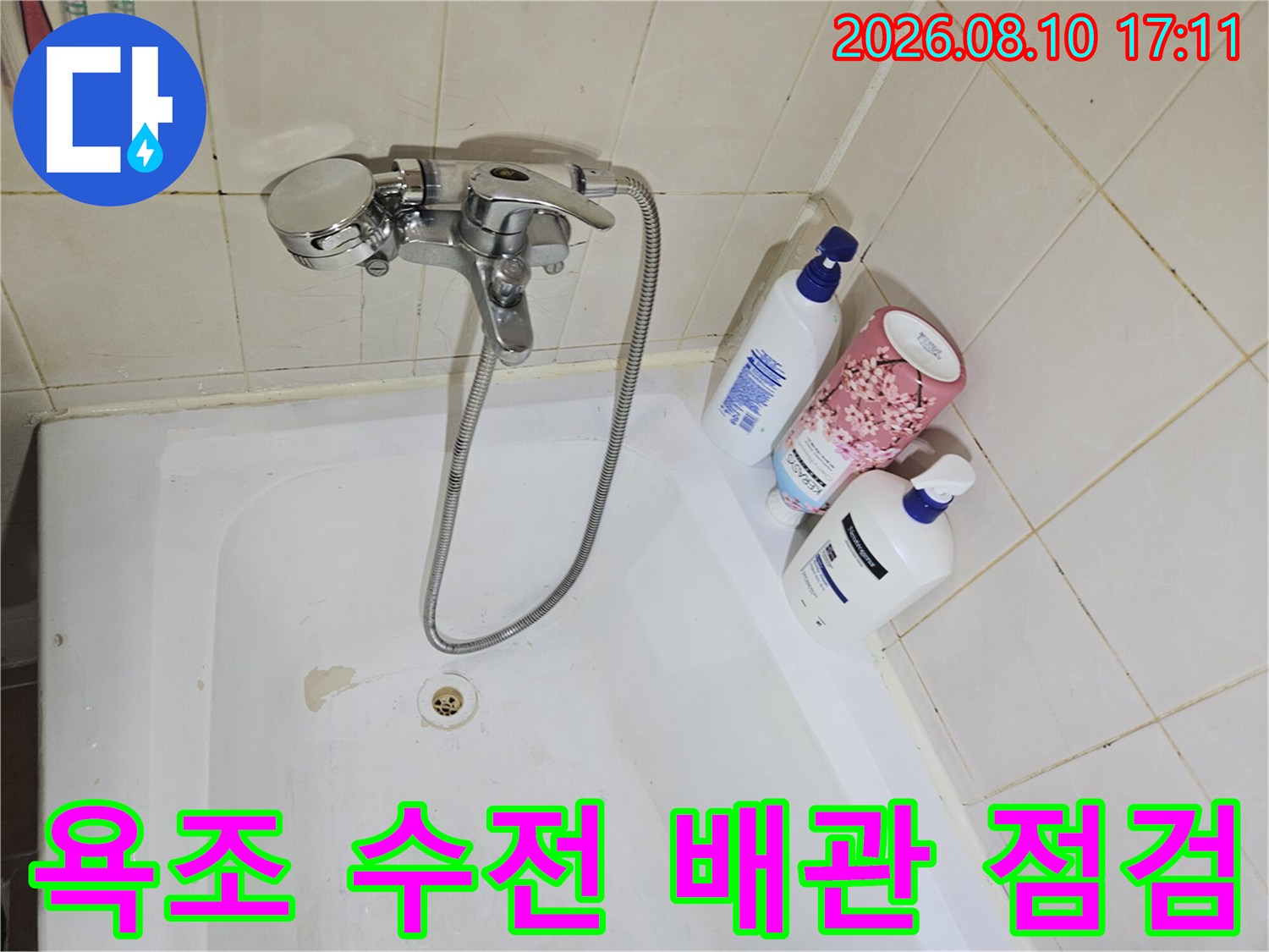 욕조에 설치된 샤워기 수전과 연결 호스의 근접 촬영본입니다.