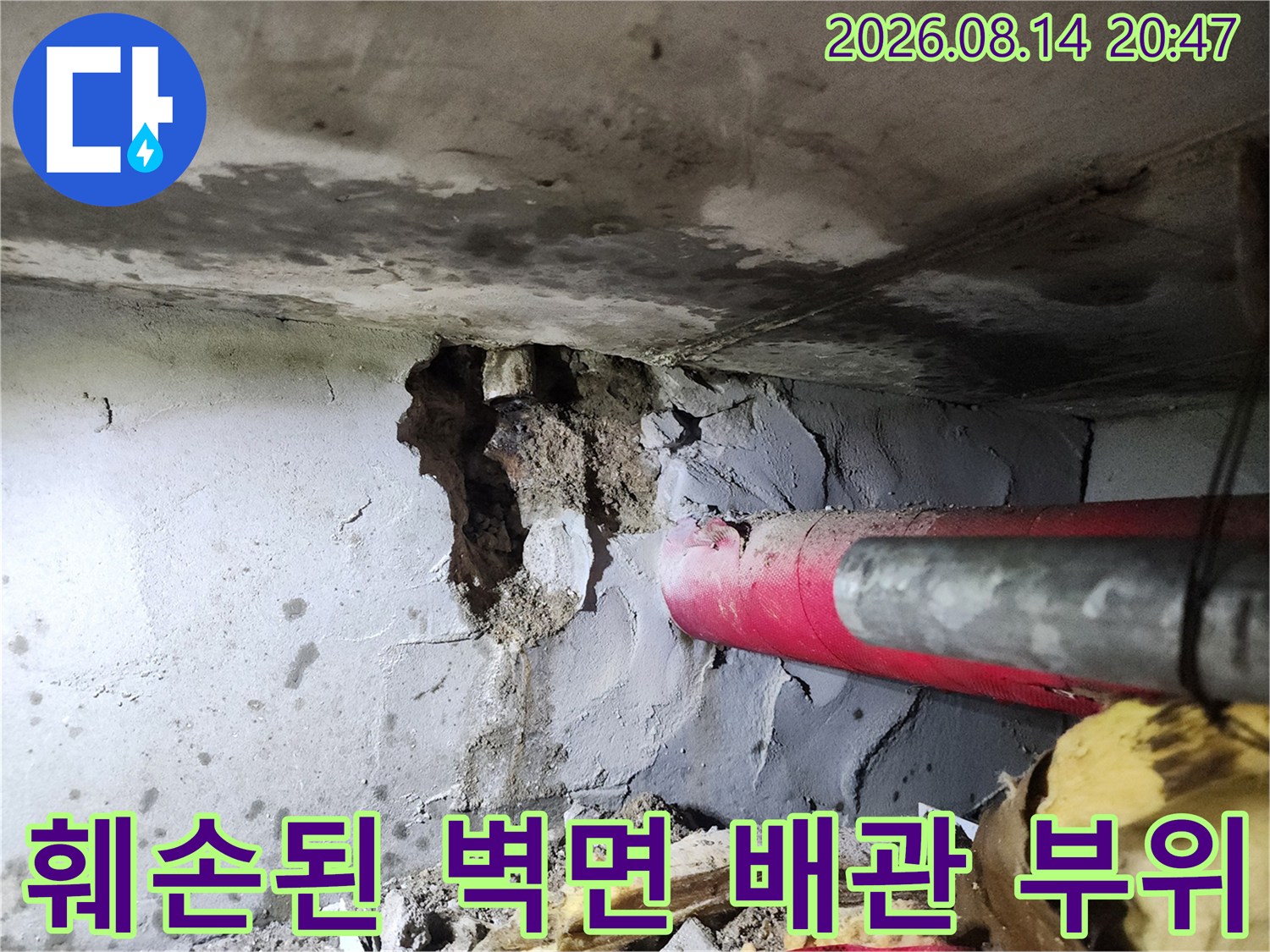 하계 부근 붉은색 배관과 누수로 손상된 시멘트 벽체