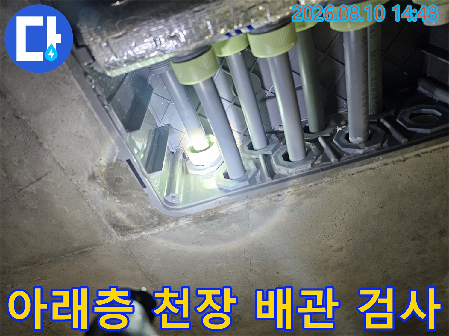 천장 내부 배관-여러 갈래의 관 연결 부위를 조명으로 확인하고 있습니다