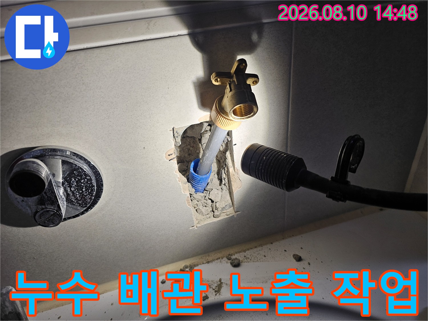 타일을 제거하여 드러난 은색 배관과 황동색 수전 연결 부위