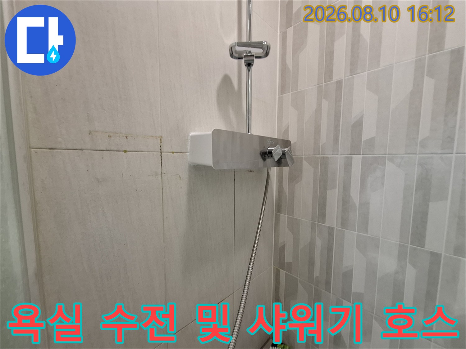 벽면에 설치된 은색 샤워기 수전과 연결된 호스 사진