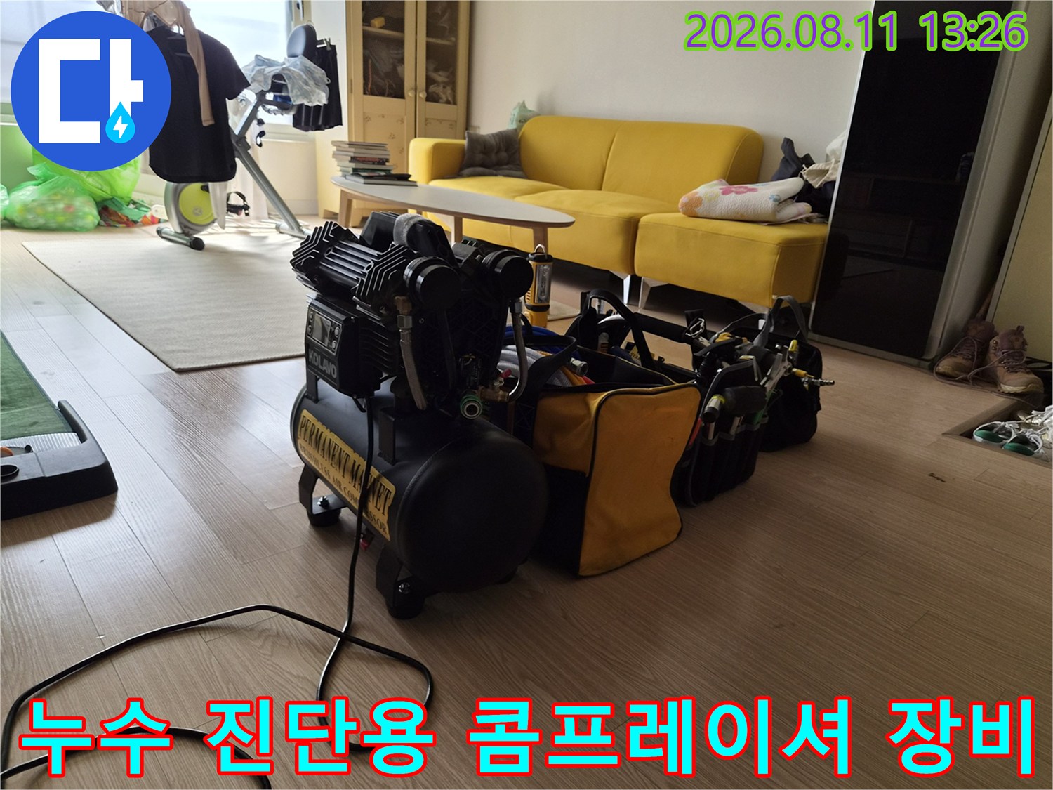 거실 바닥에 배치된-누수 탐지용 공기압 테스트용 콤프레샤와 배관 점검 도구 세트