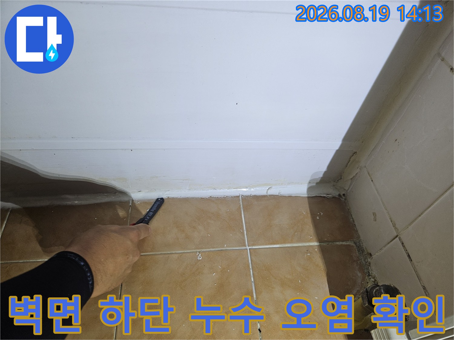 하얀 벽면 아래쪽 타일 경계의 습기 및 오염 부위 상세 촬영