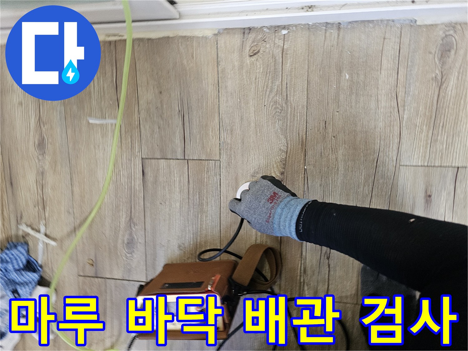나무 무늬 마루 위에서 배관 탐지 장비를 사용하는 전문가의 손