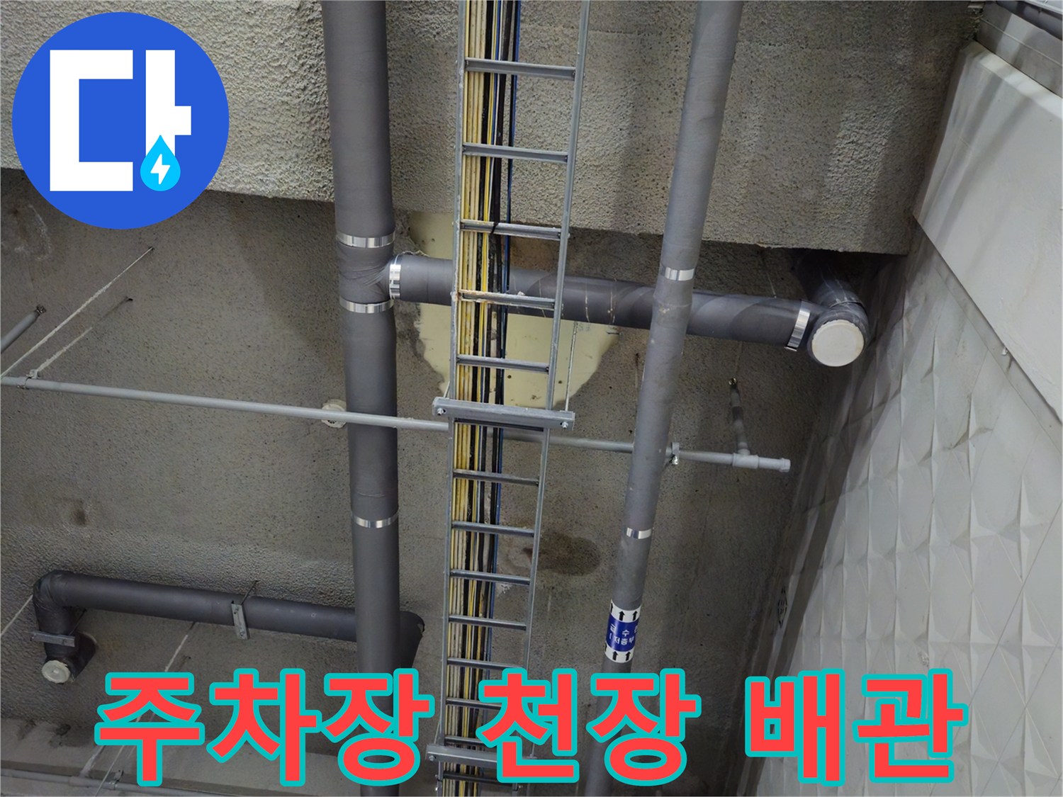 복잡한 배관과 케이블 트레이가 설치된 지하 주차장 천장 모습입니다.