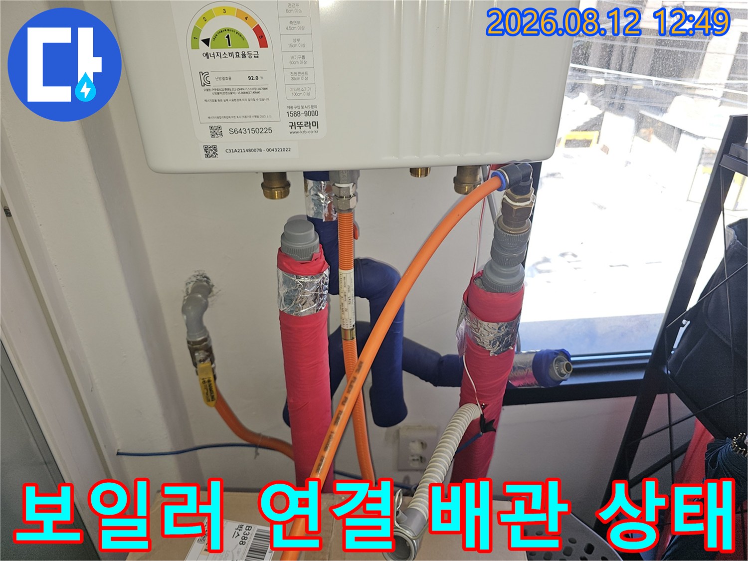 보온재로 마감된 보일러 하단 배관과 주황색 호스 연결 부위