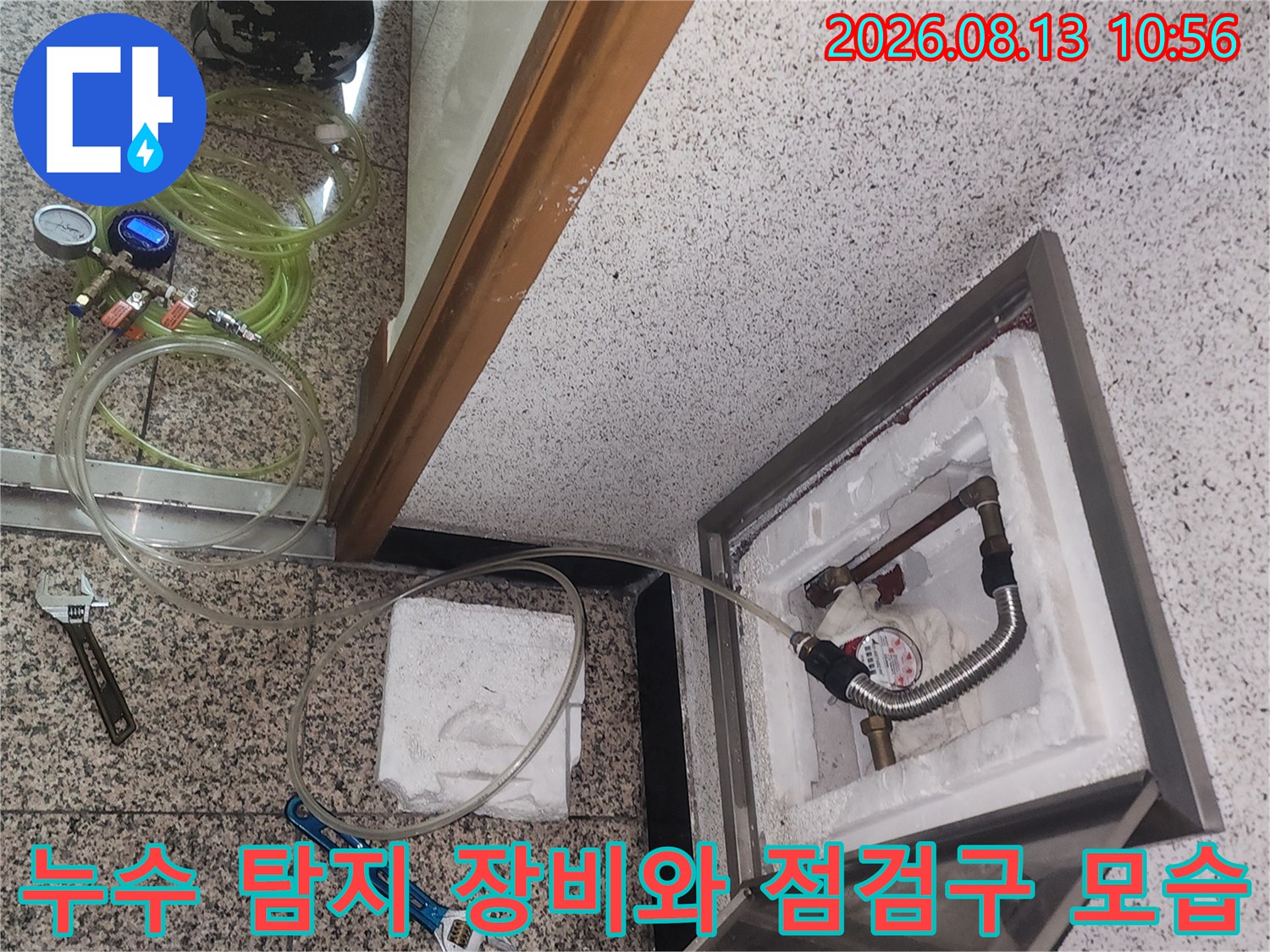 금속제 점검구 덮개가 열려 있고 내부 배관에 압력 측정기가 연결된 상태의 사진