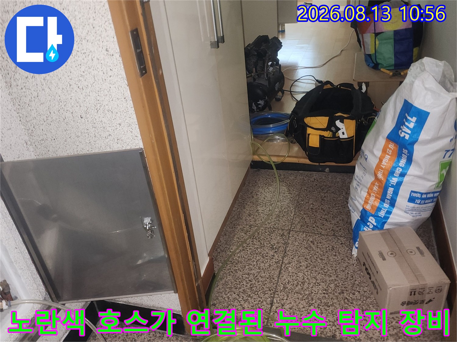 스테인리스 점검구 덮개 옆으로 배관과 노란색 공압 호스가 복잡하게 연결되어 있는 장면