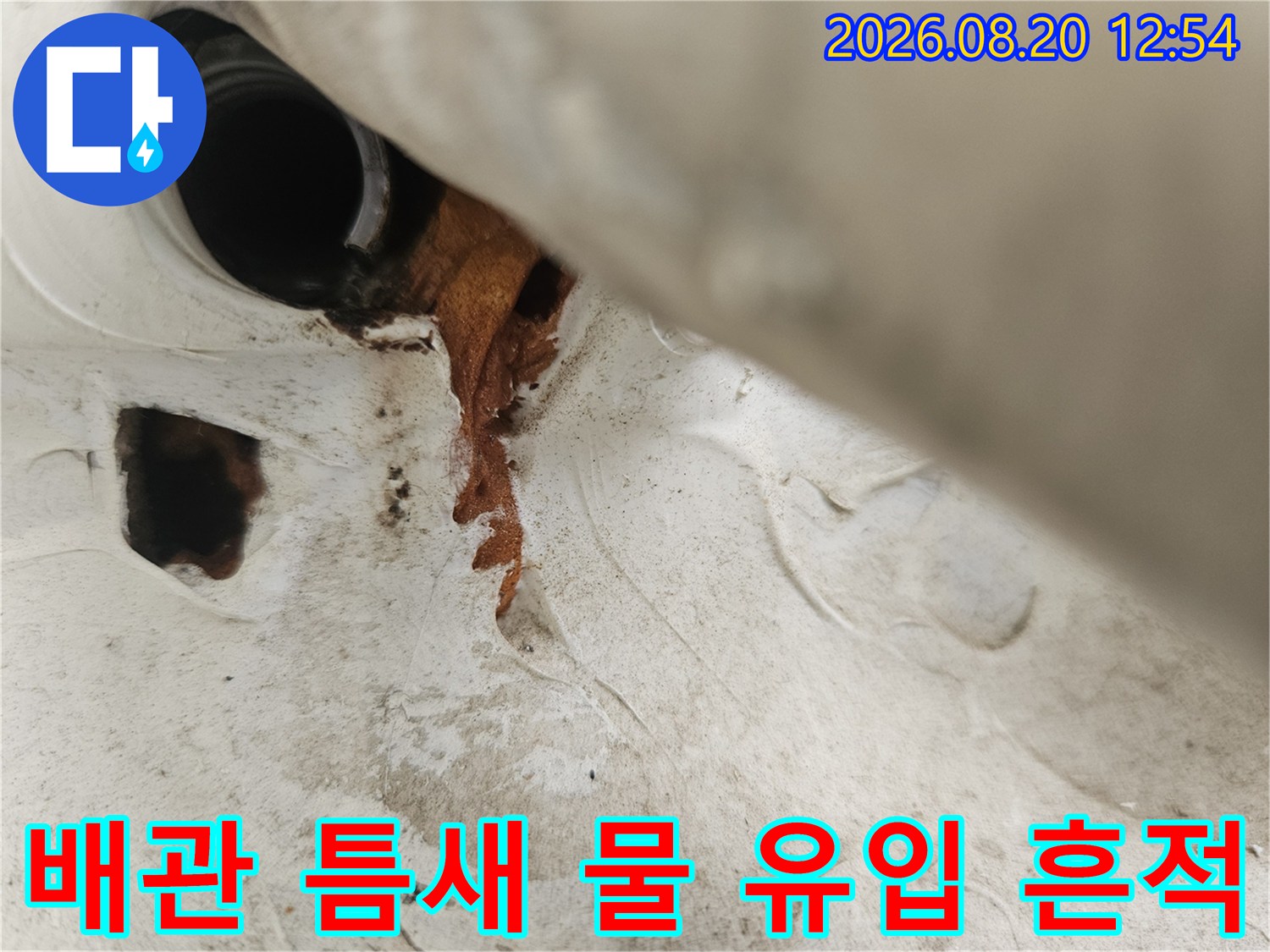 우수관 배관과 벽체 사이의 갈색 누수 자국 및 변색된 마감재