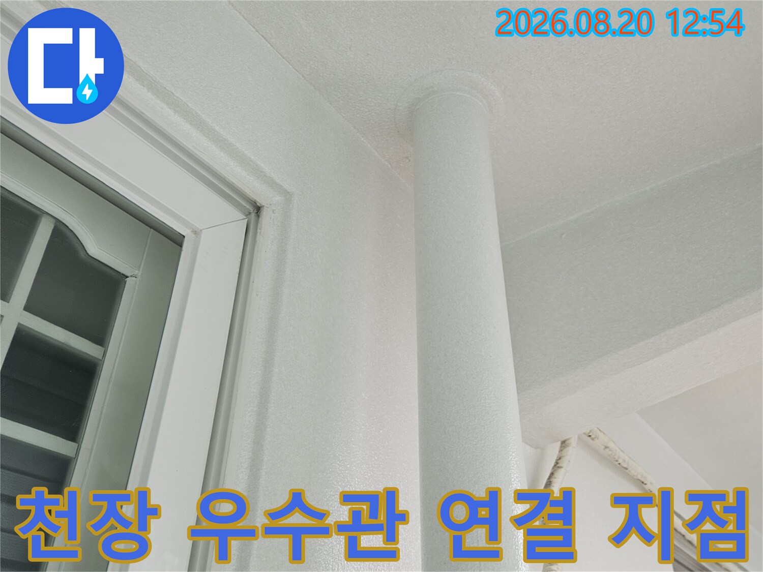 하얀색 수직 배관과 천장 구조물이 만나는 경계 부위 촬영