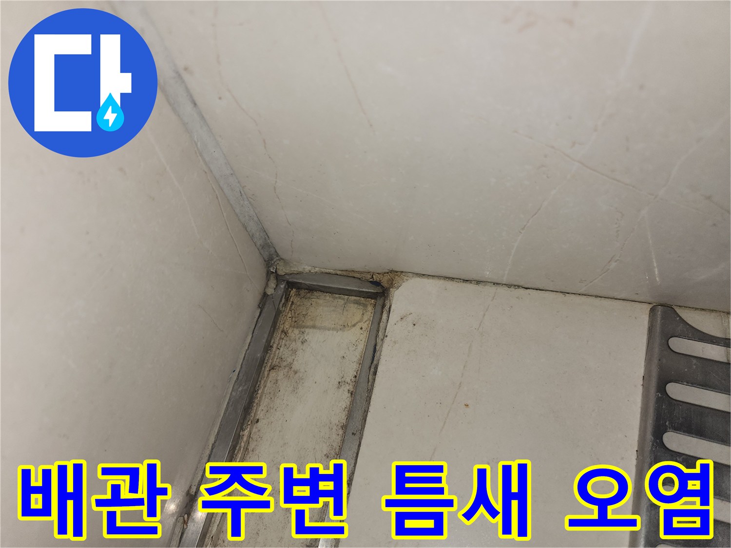싱크대 하부 배관 연결 부위 주변의 젖은 타일과 먼지 뭉침