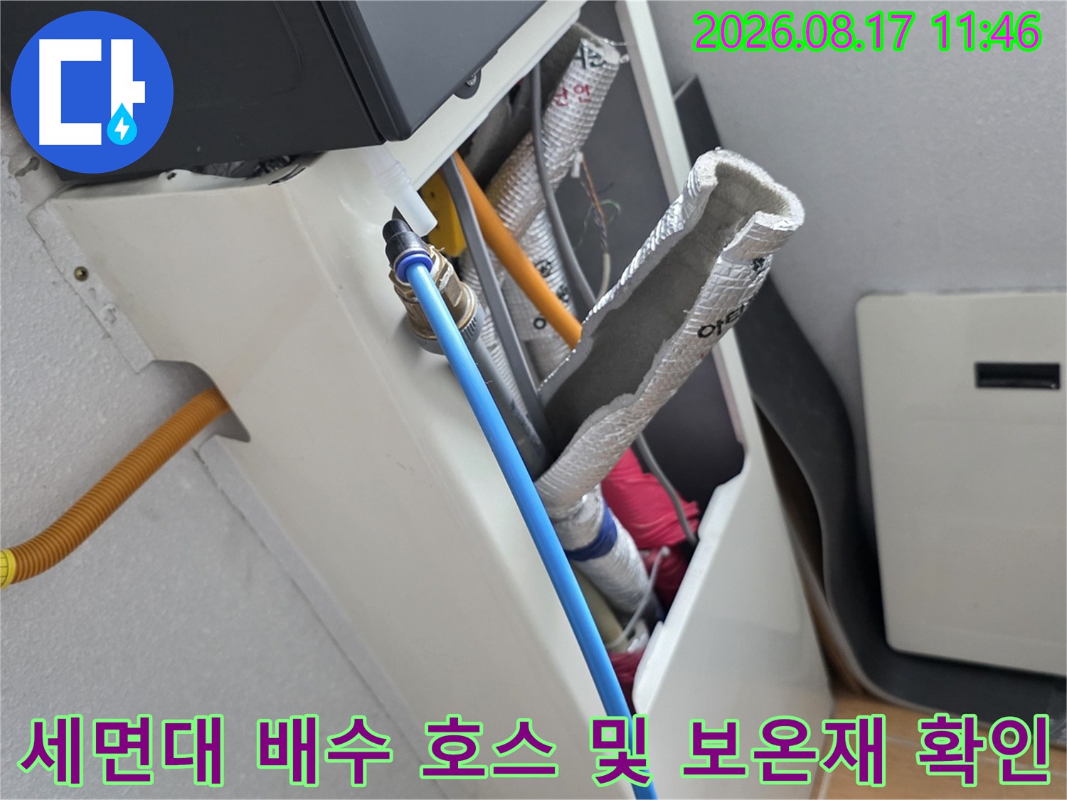 은박 보온재로 감싸진 배관과 파란색 급수 호스의 연결 상태를 점검하는 장면