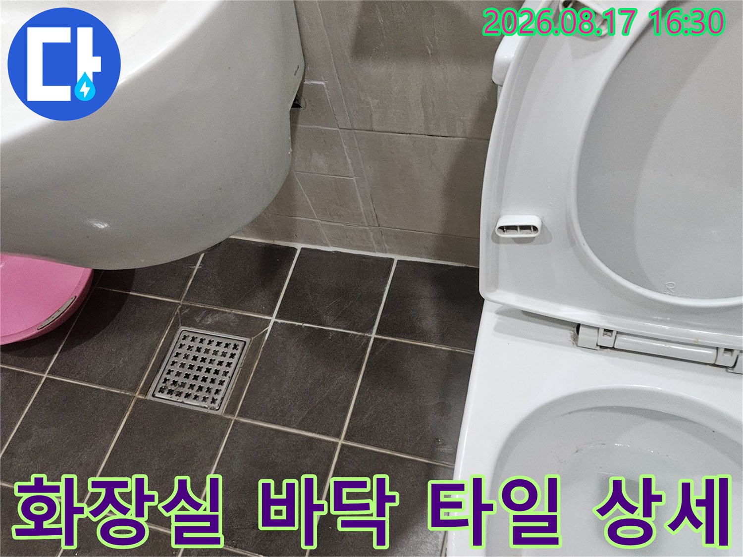변기와 세면대 주변의 어두운 타일 모습입니다.