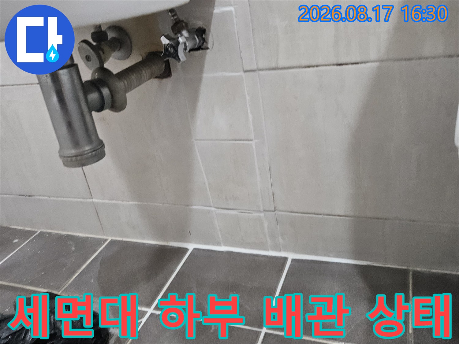 세면대 아래쪽 냉수 공급 배관과 타일 벽면 모습입니다.