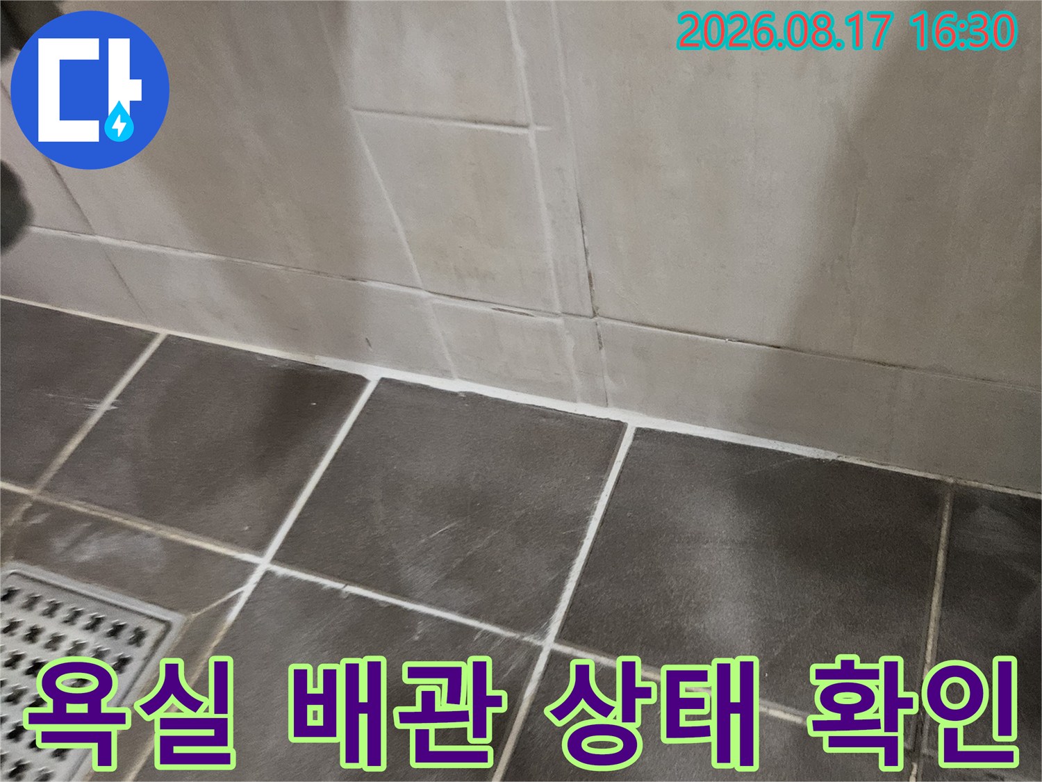 어두운 타일 바닥-세면대 하부 배관 연결 부위 점검 중