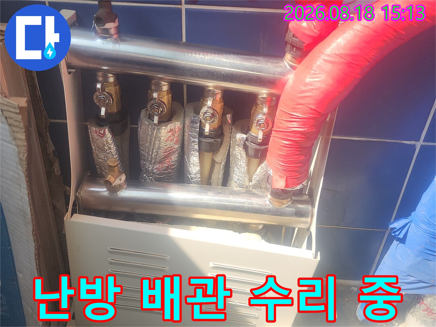 보온재로 감싸진 배관과 분배기 부속의 교체 작업 장면입니다.
