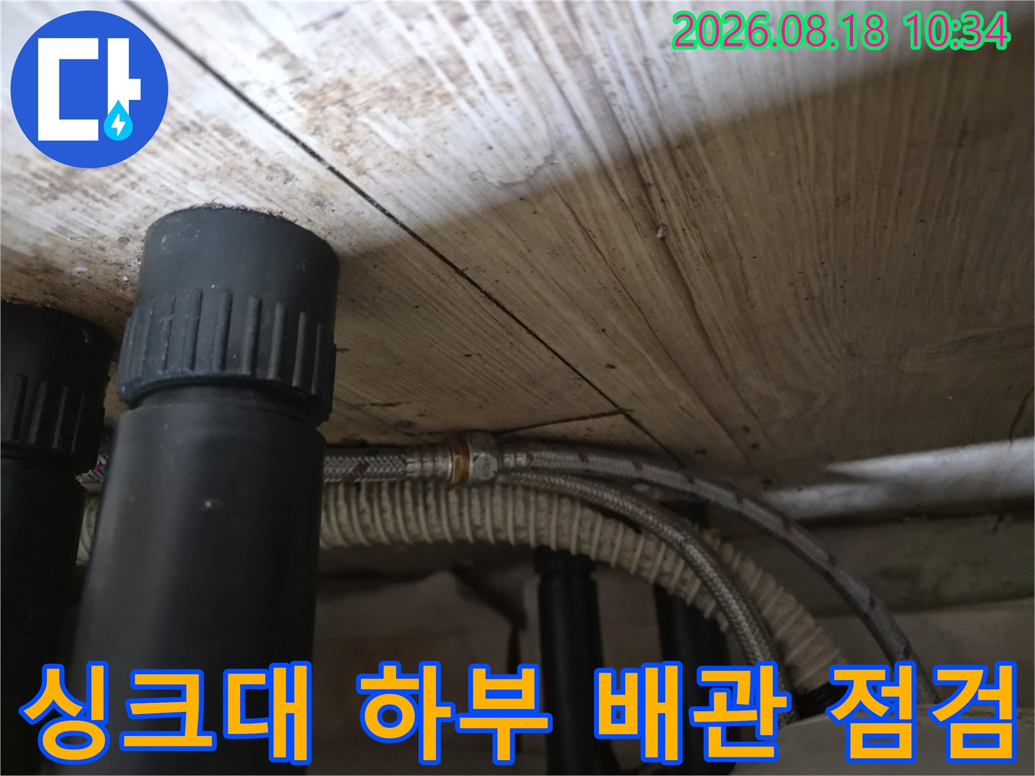 싱크대 아래 검은색 배관과 은색 호스가 연결된 사진입니다.