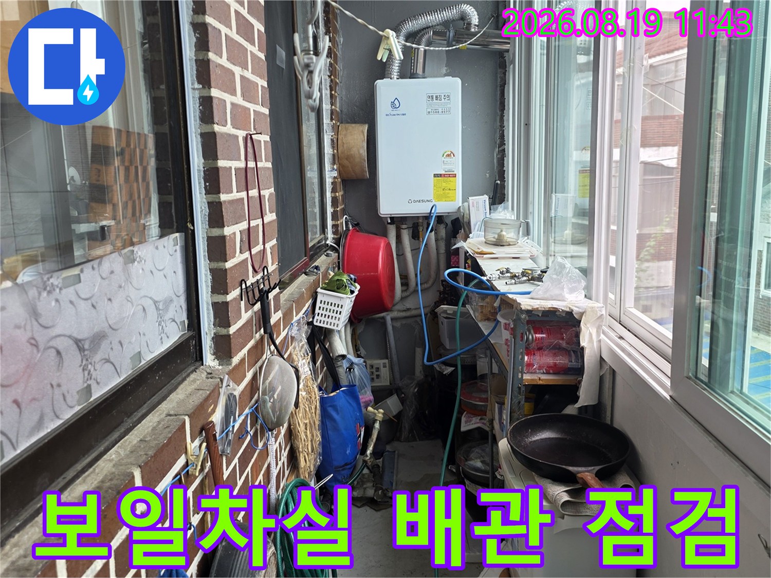 벽돌 벽면에 설치된 보일러와 외부로 연결된 배관의 모습입니다