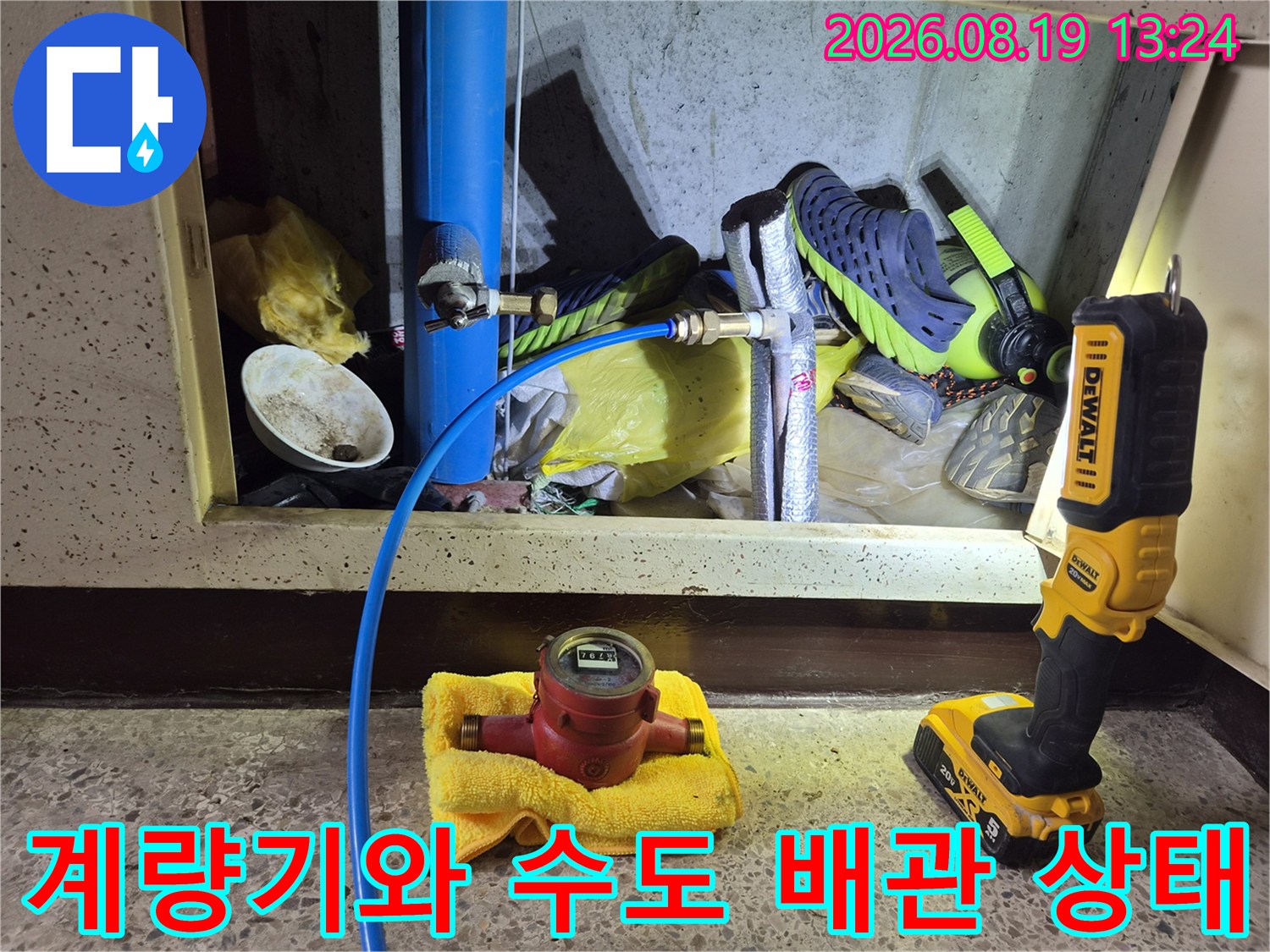 파란색 수도 배관과 계량기가 놓여 있는 싱크대 하부 점검 사진