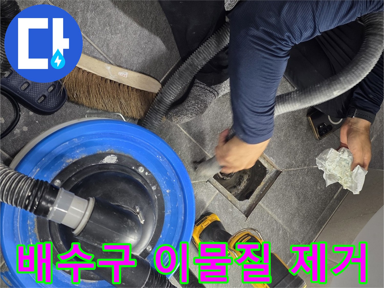 배수구 주변의 찌꺼기를 청소기로 흡입하는 작업 장면