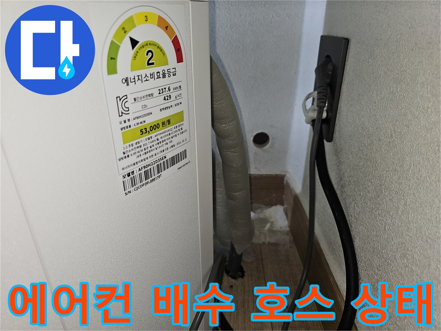 에어컨 본체 하단에서 연결된 드레인 호스와 벽면 콘센트 모습