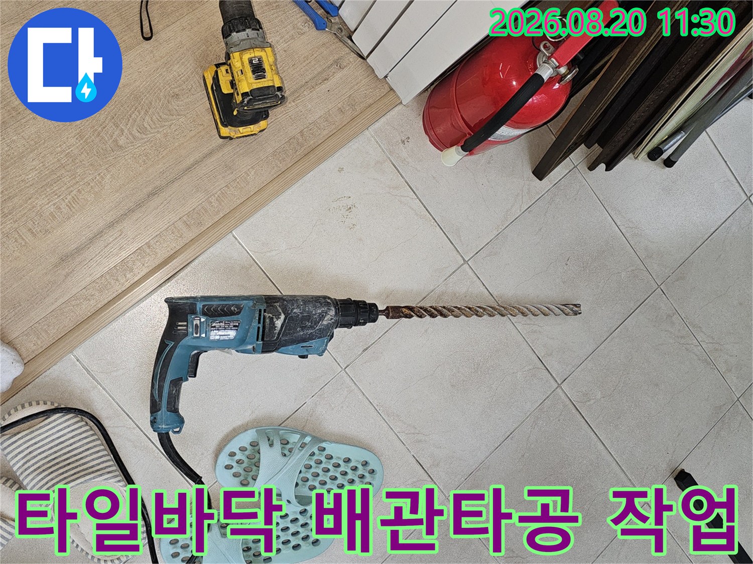타일 바닥 위에서 진행 중인 에어컨 드레인 배관 타공 작업 현장입니다.