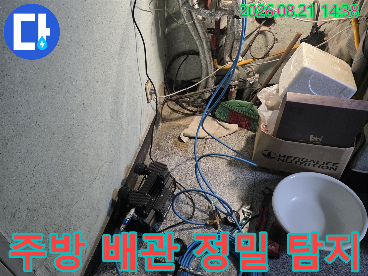 싱크대 아래 배관 구역에 배치된 가스 탐지 장비와 호스