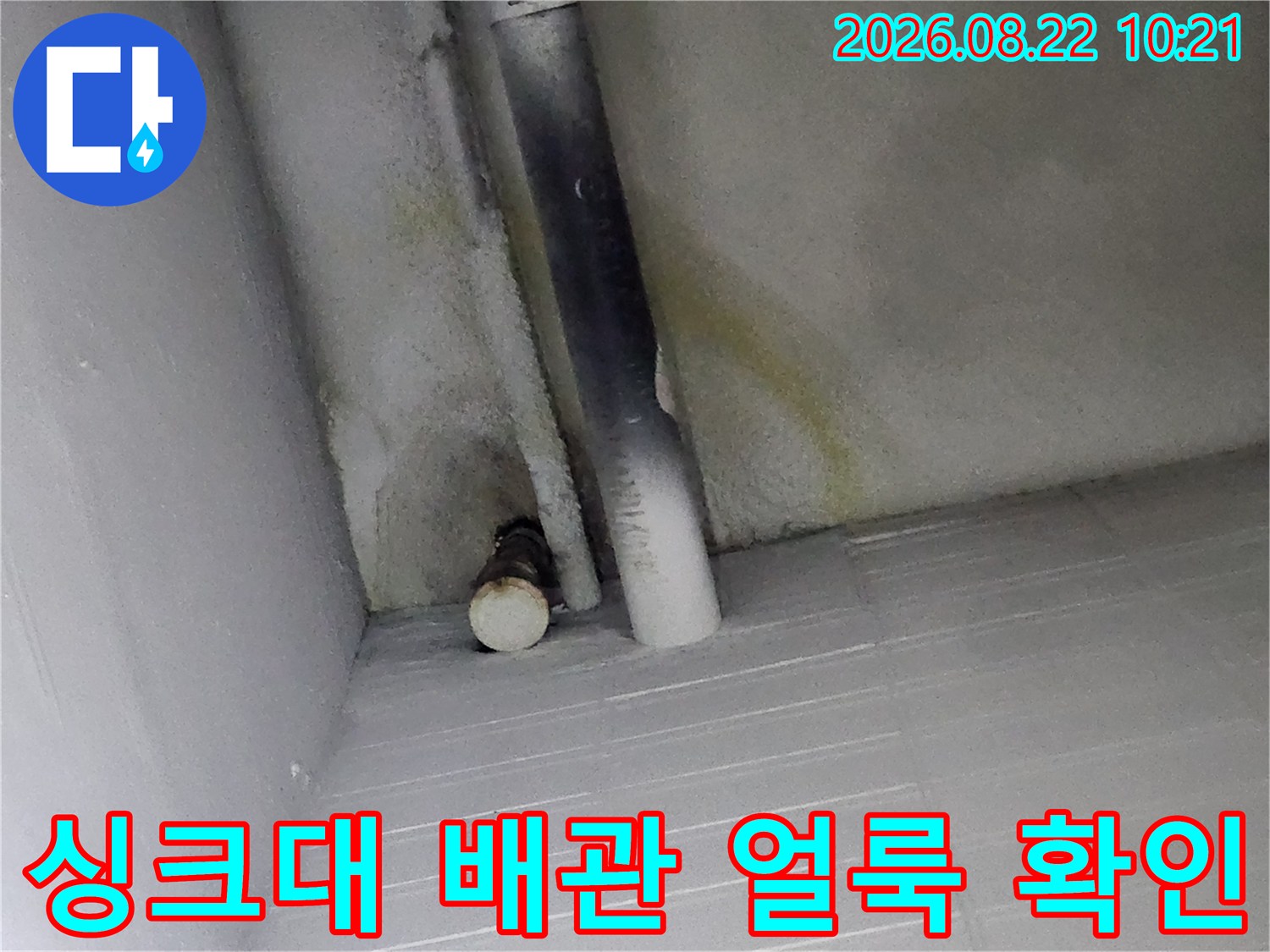 싱크대 하부장 배관 주변에 발생한 누수 흔적과 얼룩 상태를 점검하는 모습입니다.