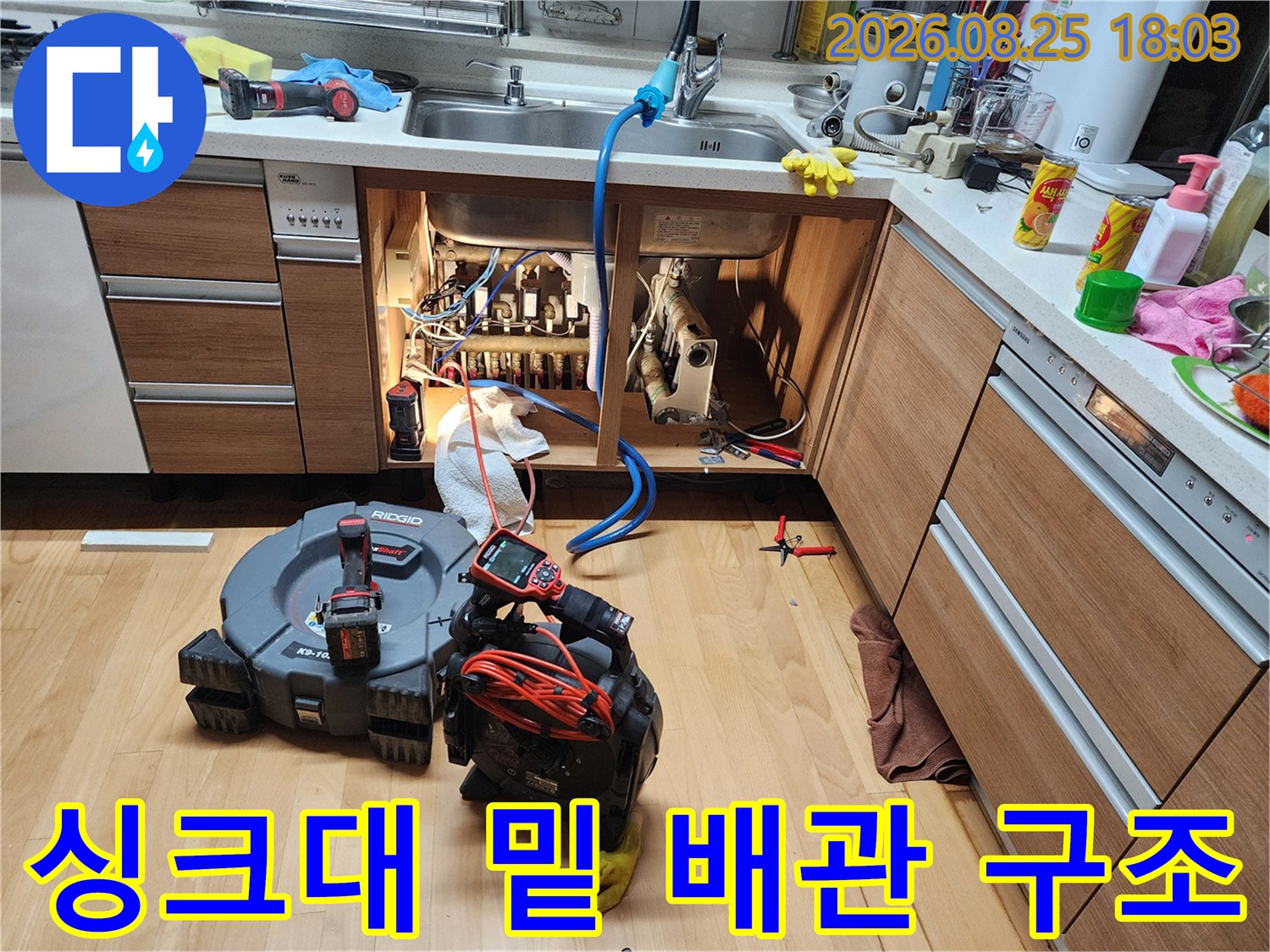 싱크대 수납장 내부의 복잡한 급수 및 배수 배관과 작업용 전동 공구들