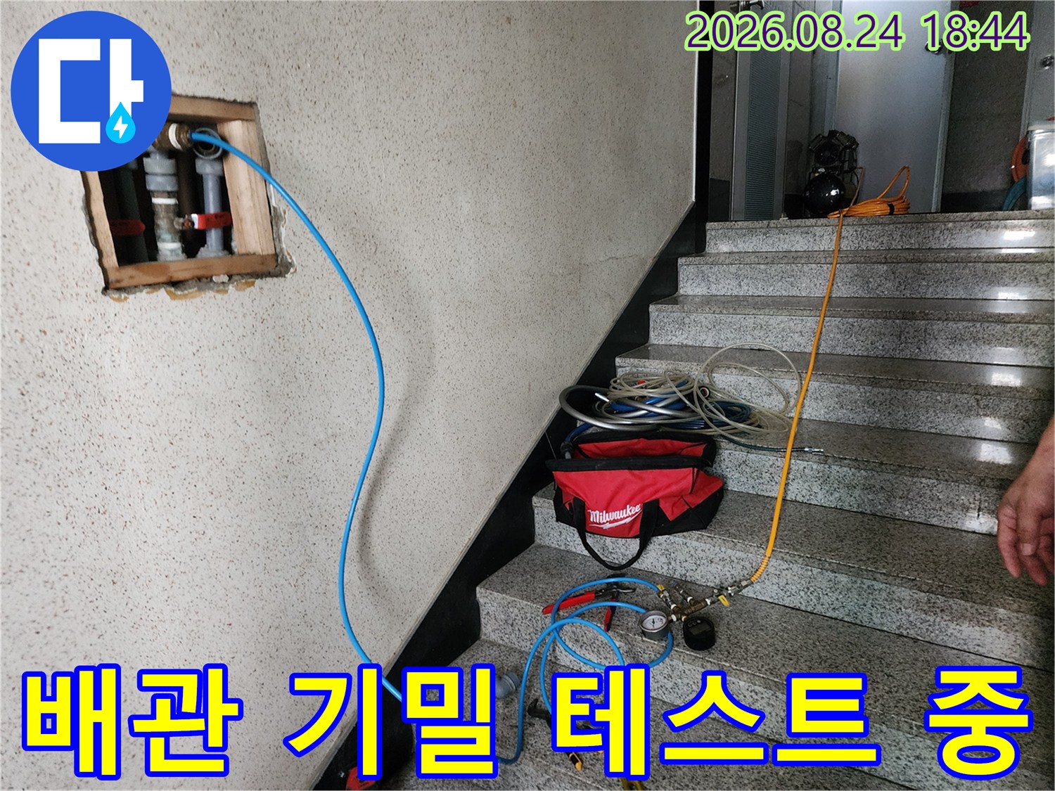 벽면 배관 노출 부위에 압력계를 연결하여 누수를 점검하는 작업 현장