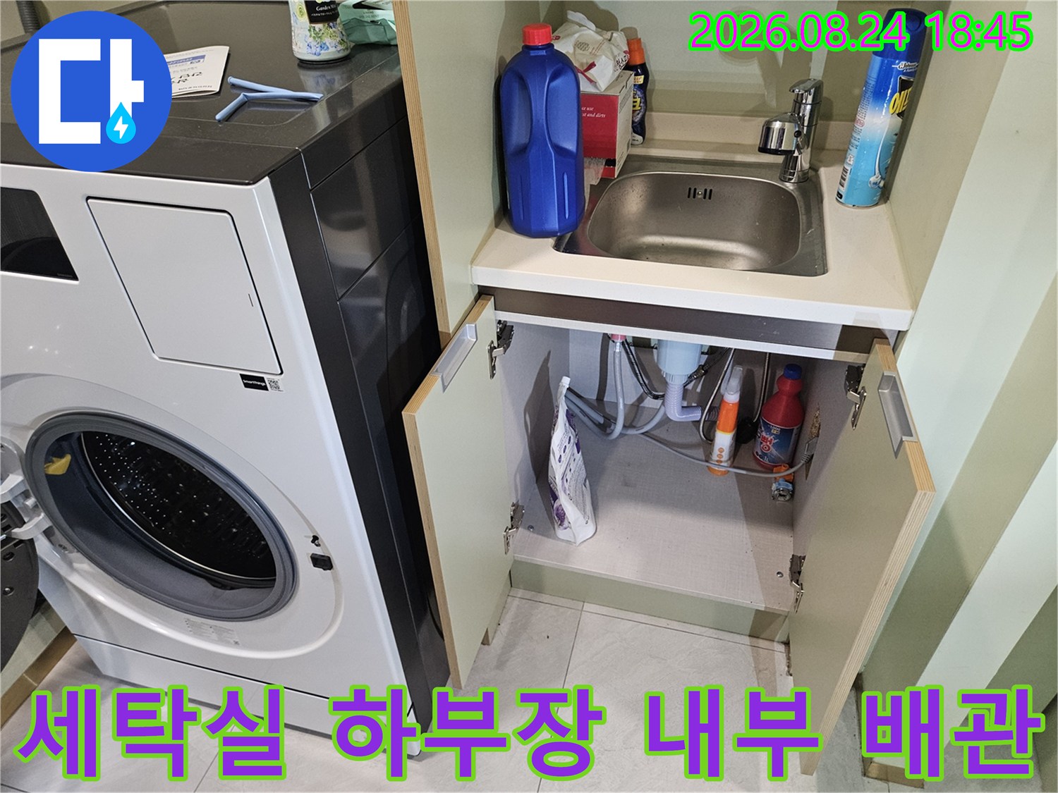 세탁기 옆 하부장에 놓인 세제와 배관 연결 부위