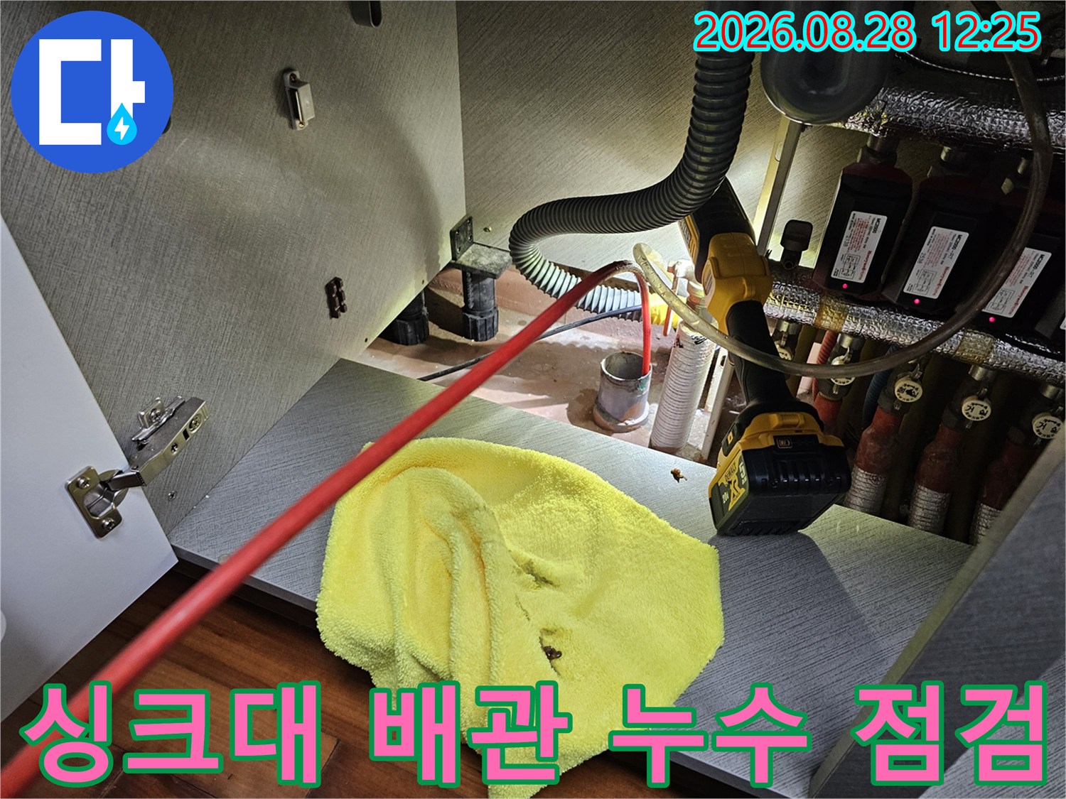 싱크대 하부장 내부의 복잡한 배관과 작업 도구 배치 상태