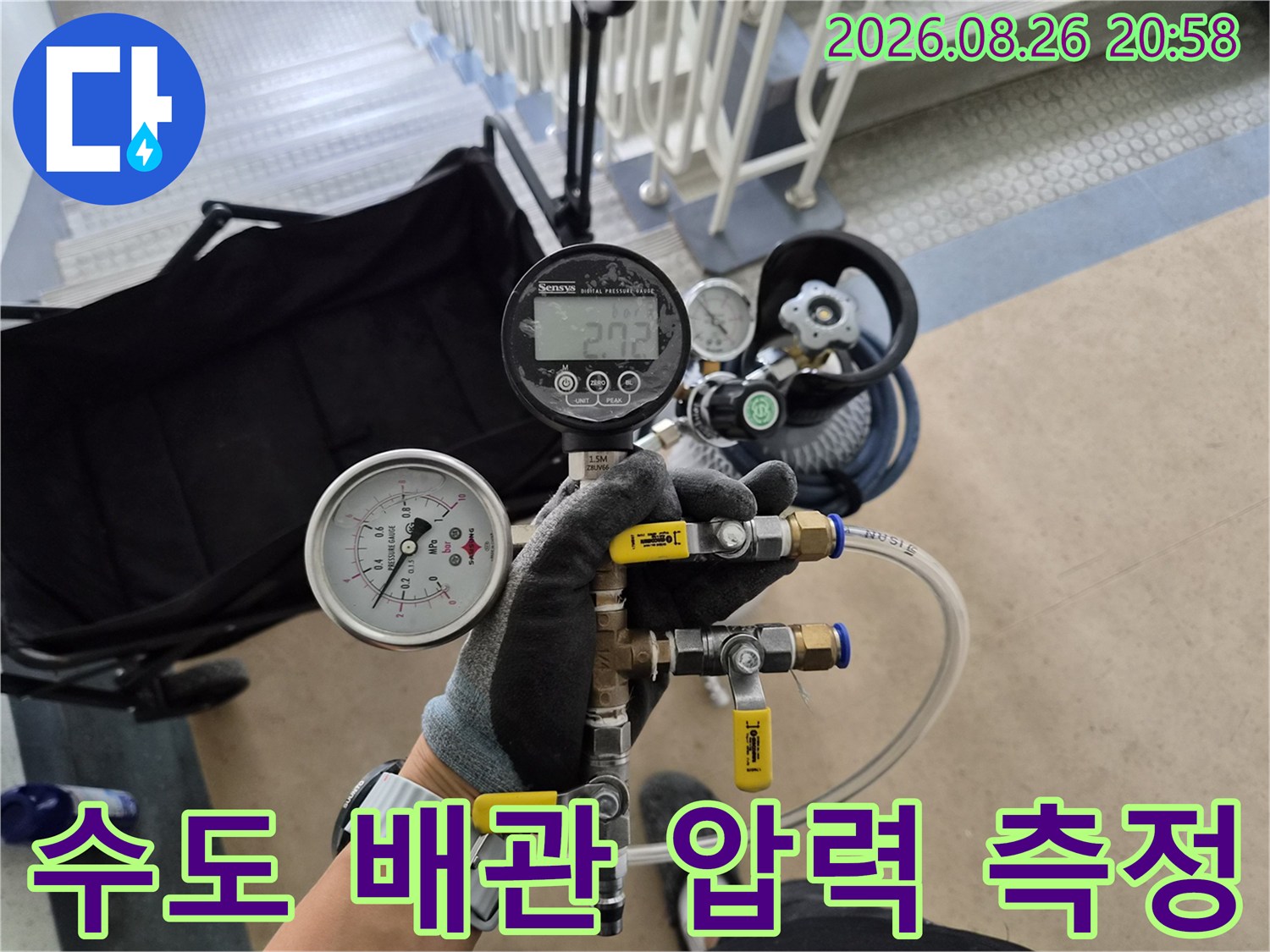 밸브와 압력계가 연결된 장비를 사용하여 배관을 점검하고 있습니다.