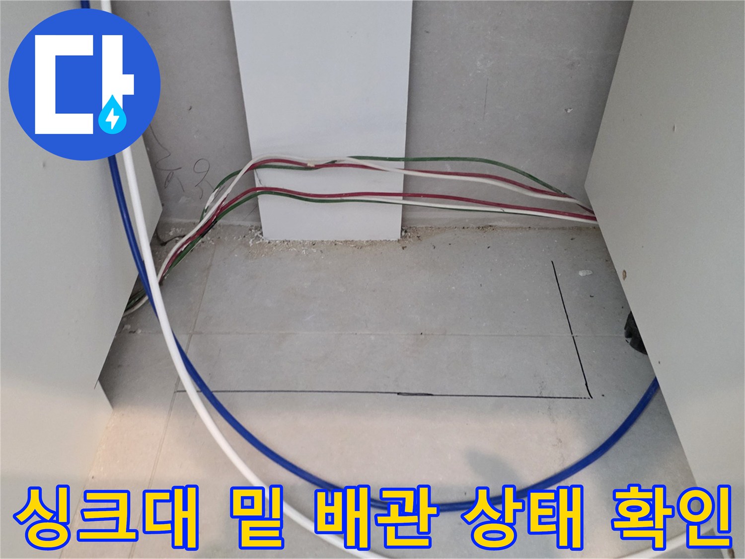 싱크대 아래 공간에 보이는 노출된 배관과 전선