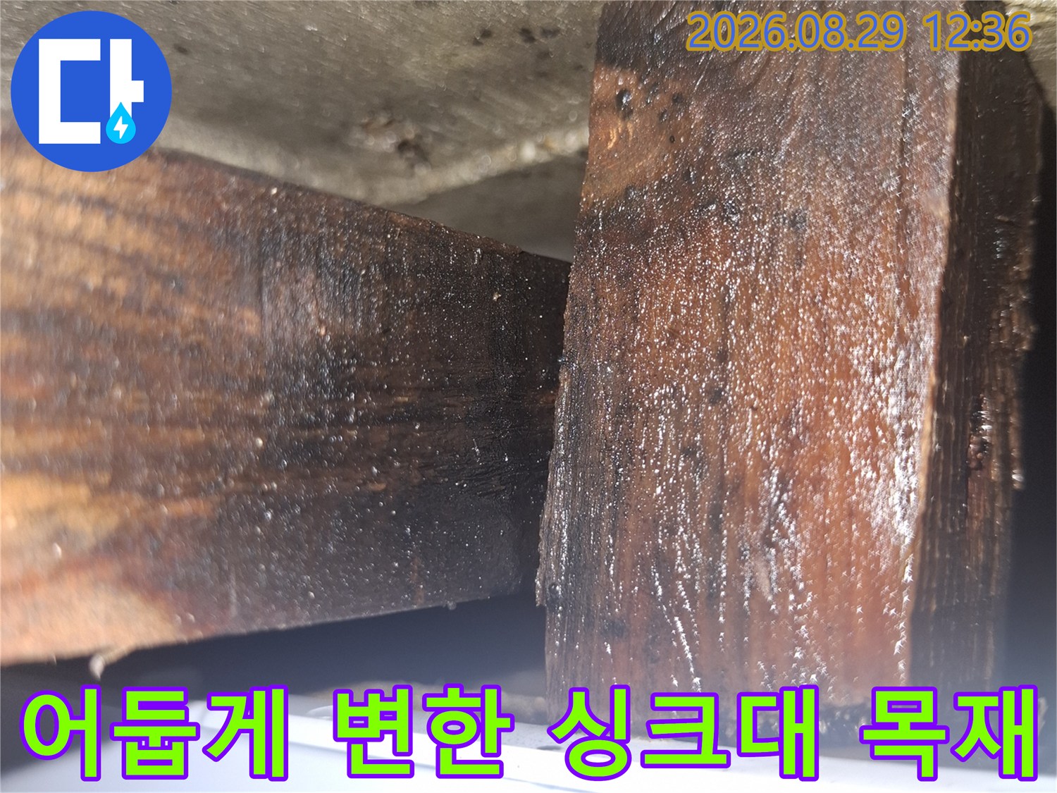 싱크대 하부 부재-습기 유입으로 인해 짙게 오염된 나무 표면