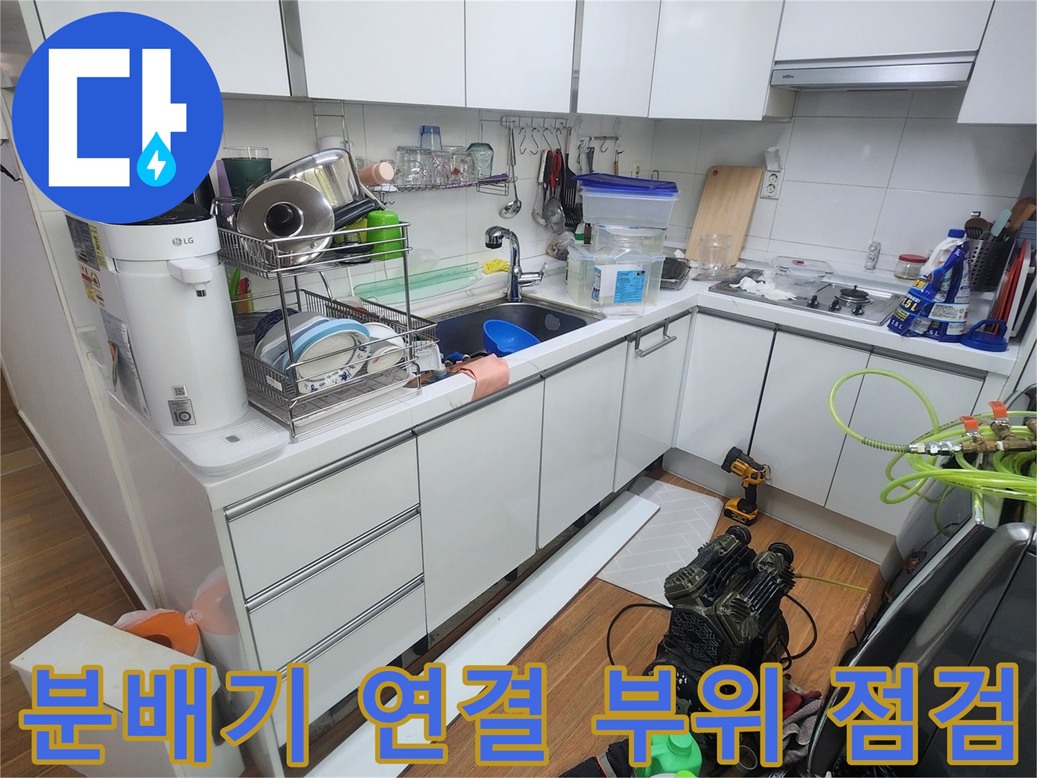 싱크대 하부장의 보일러 분배기와 각종 배관들이 복잡하게 설치되어 있습니다.