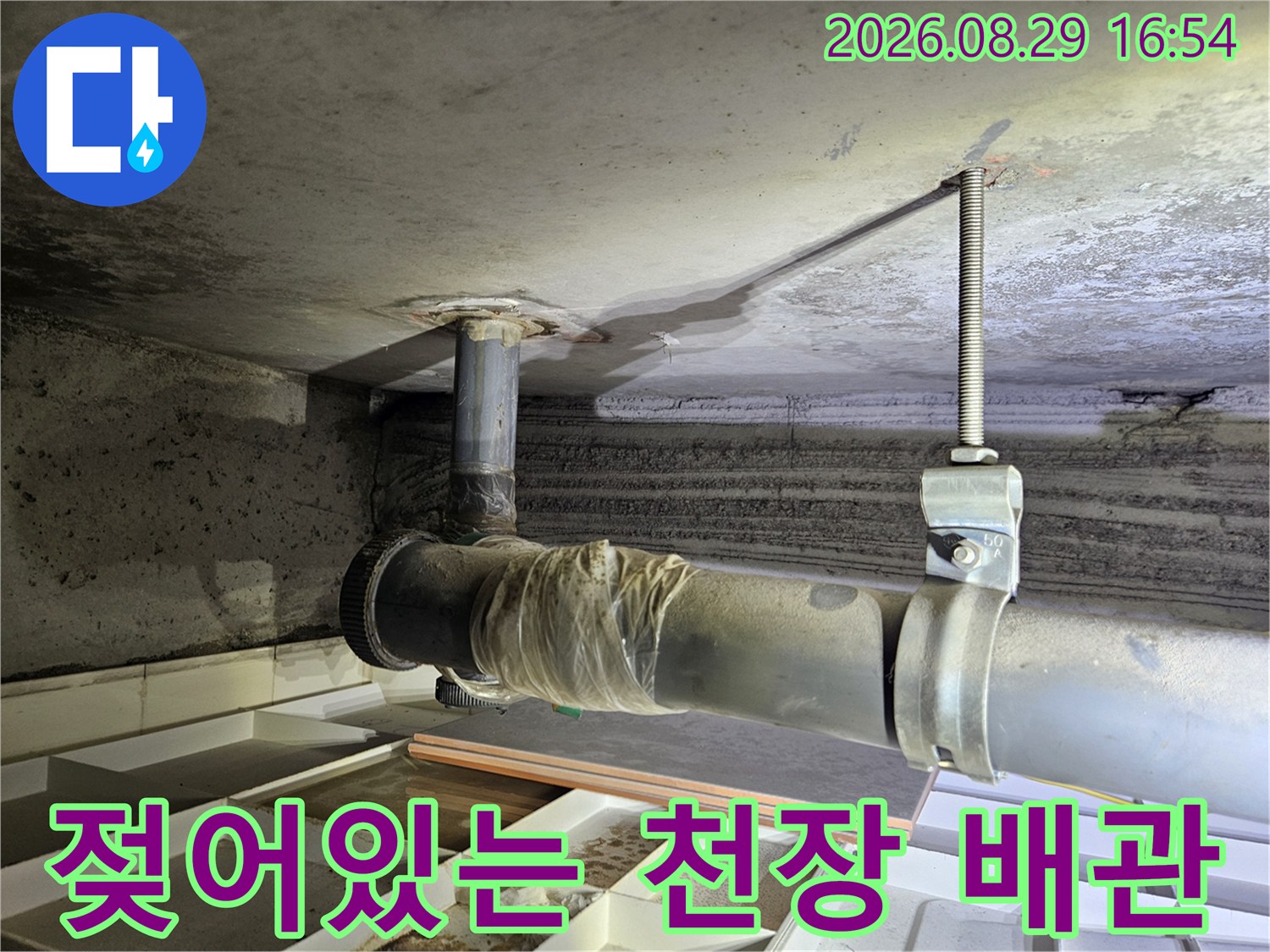 배관 주변 콘크리트 슬래브에 발생한 젖은 얼룩과 습기 상태를 보여줍니다.