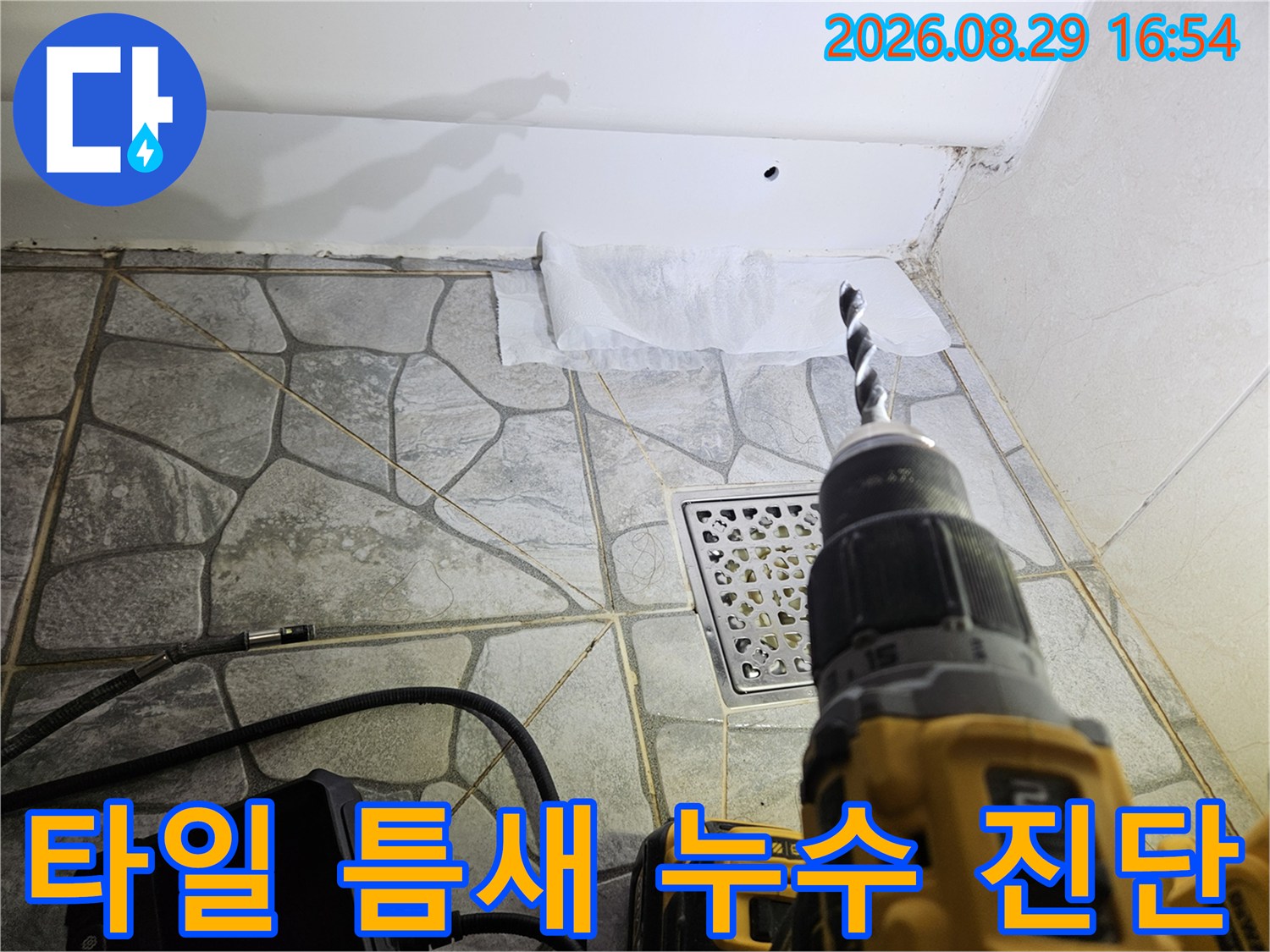 배수구 근처 타일 줄눈과 마감재 상태를 점검하는 작업자