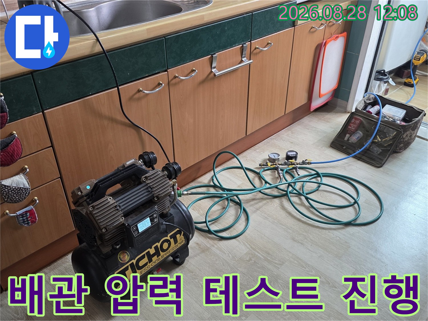 주방 싱크대 하부 배관에 연결된 공압 장비와 호스 라인