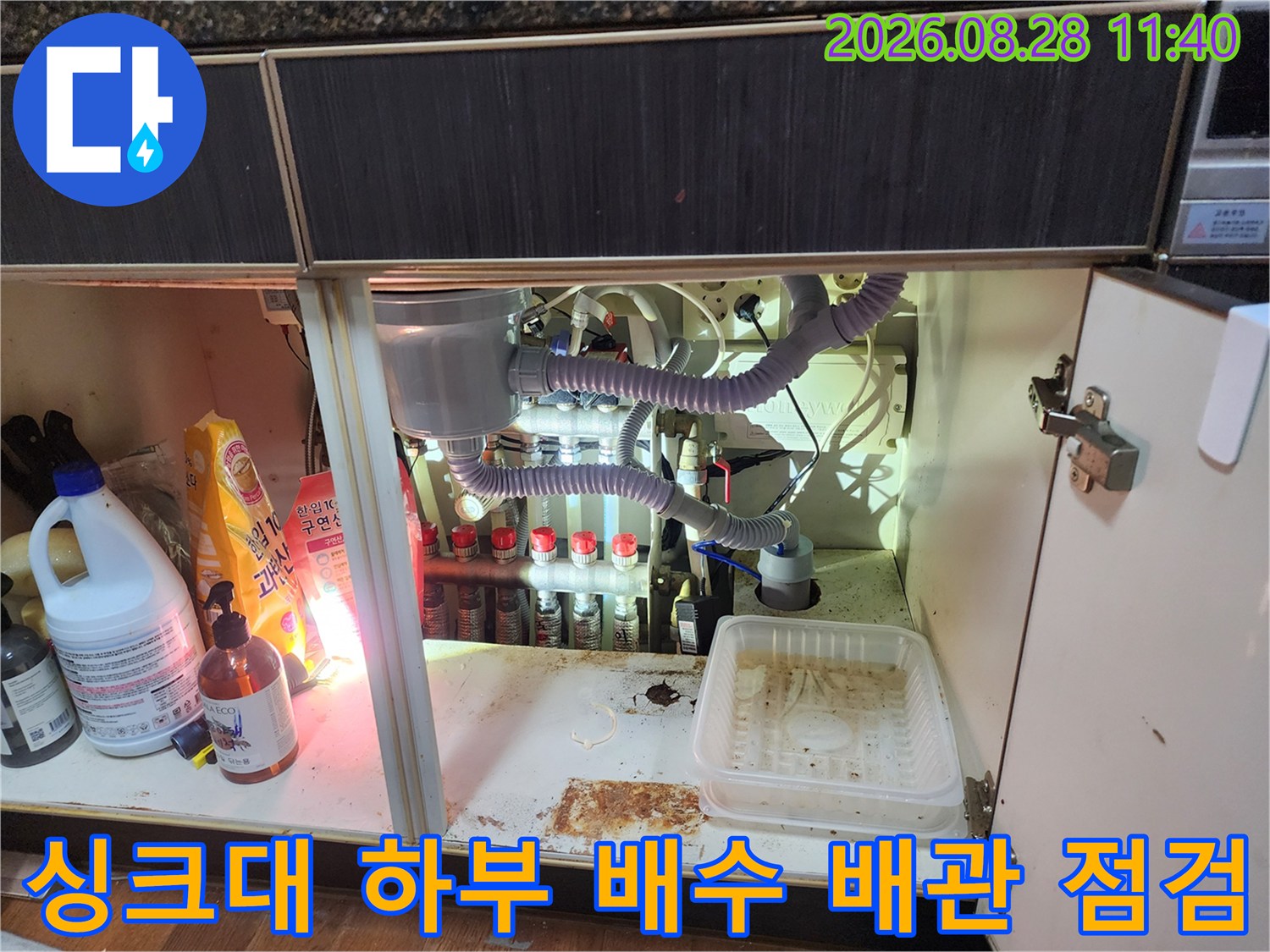 싱크대 하단 내부의 에어컨 드레인 호스와 여러 배수 연결 부위