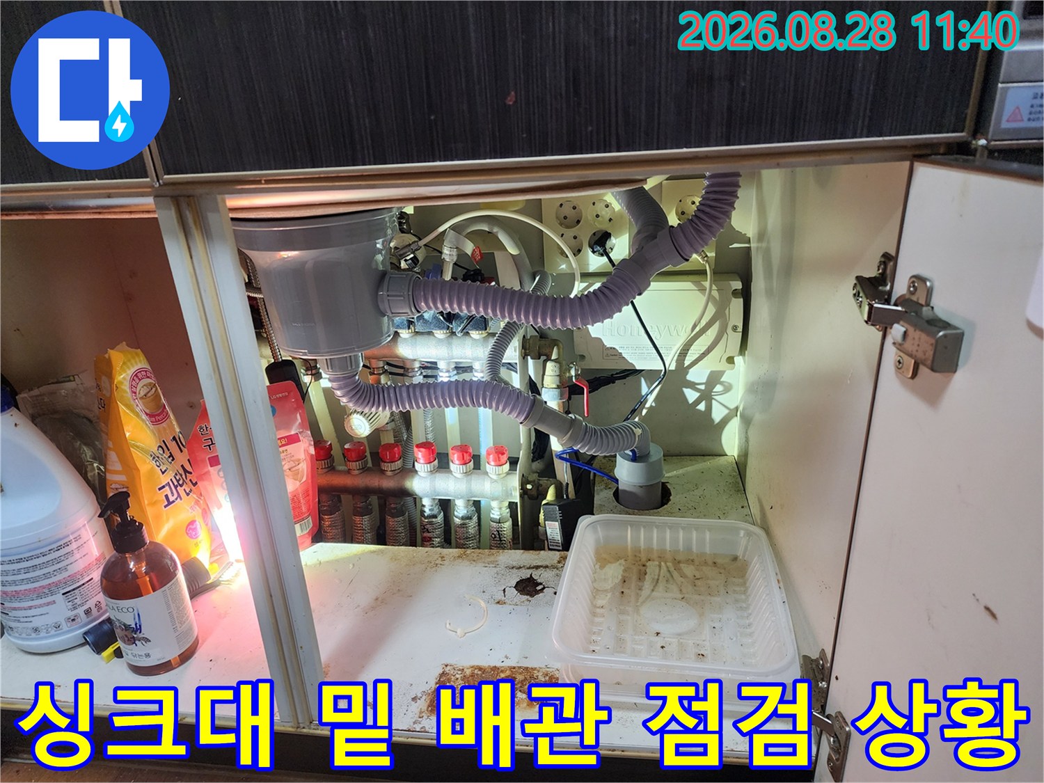 싱크대 하단 정수기 필터와 에어컨 드레인 호스 연결 부위의 상세 모습