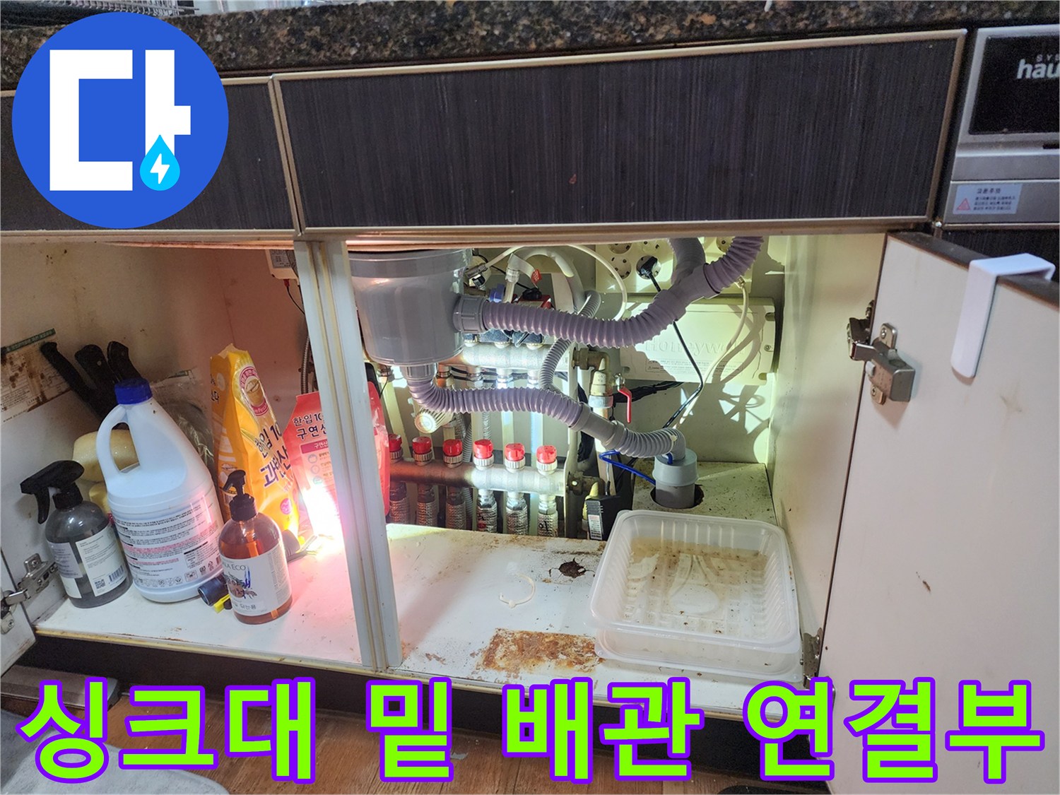 싱크대 하단에 배치된 다양한 크기의 배수 호스와 분기 장치들