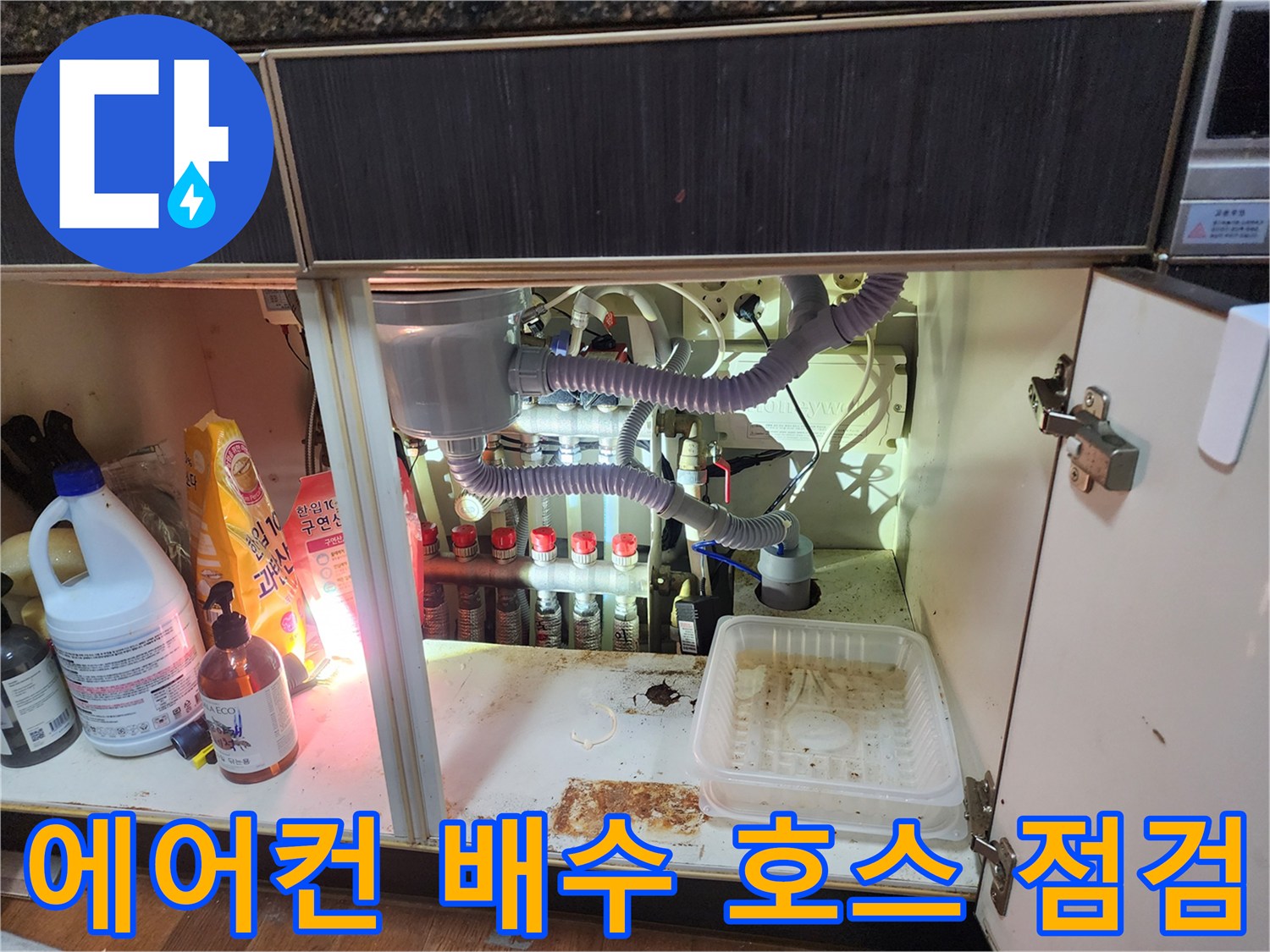 싱크대 하부장 안쪽의 에어컨 배수 관로 및 싱크대 배관 연결 모습