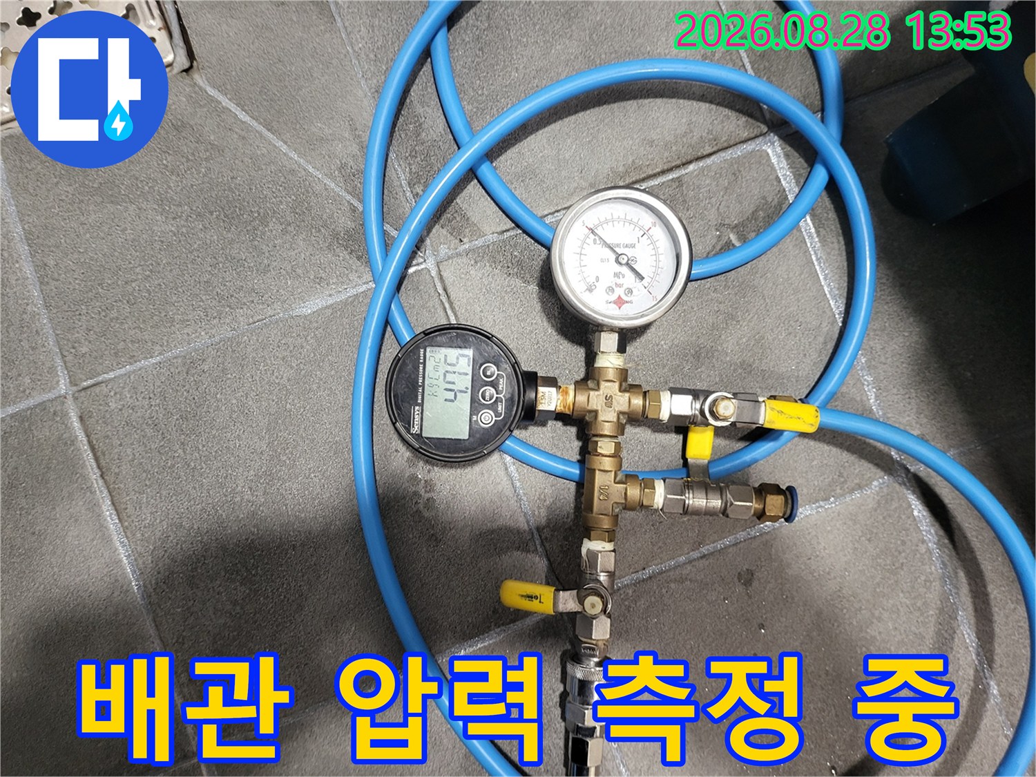 파란색 호스가 연결된 배관 압력 측정용 밸브와 게이지 장비입니다.