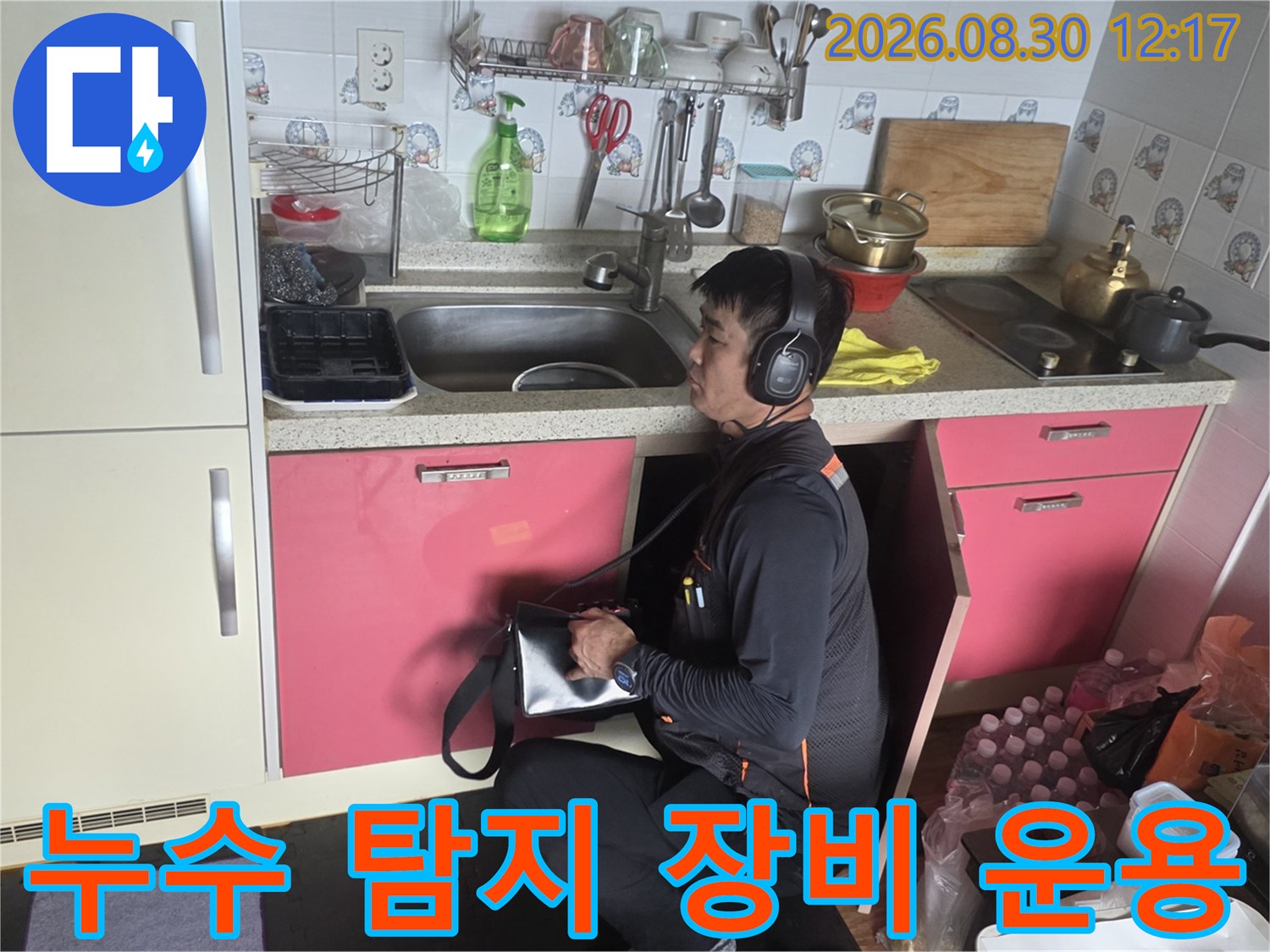 싱크대-하단-공간에서-전문-장비를-활용해-누수음을-듣고있는-작업자