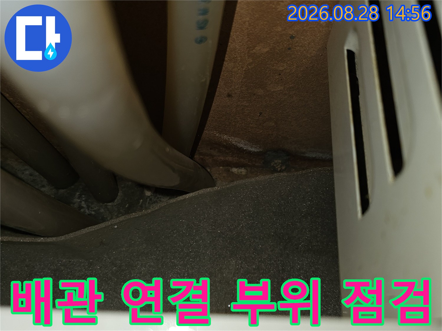 싱크대 밑 배관의 굴곡진 부분과 벽면 경계 지점을 촬영한 사진입니다.