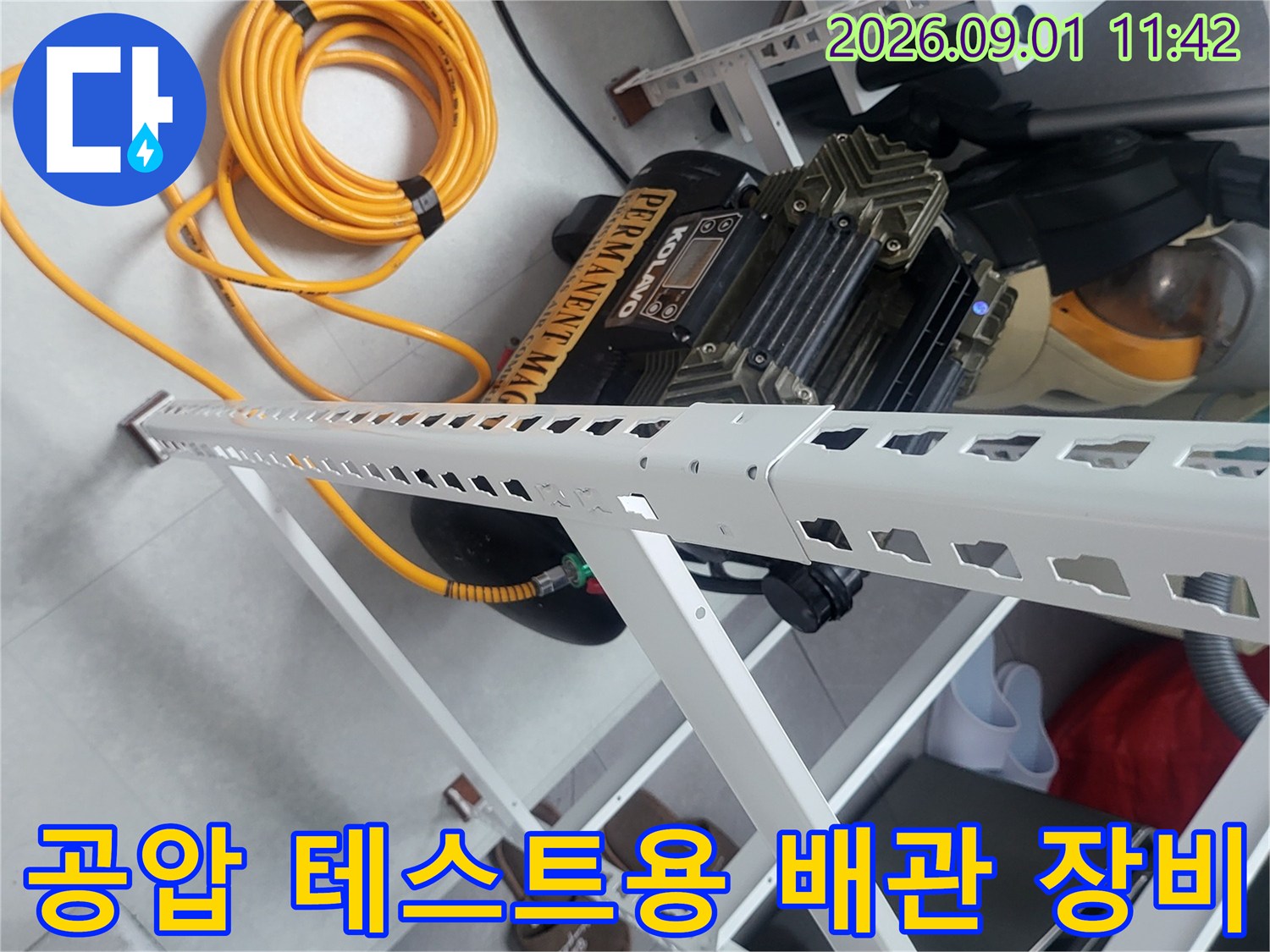 선반 아래 놓인 누수 탐지용 공압 기계와 노란색 에어 호스 뭉치