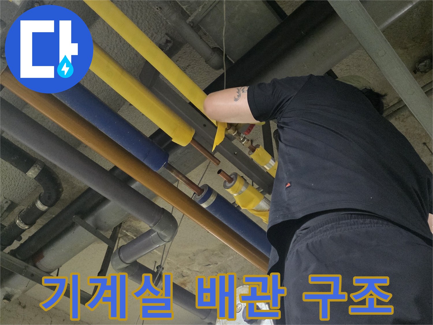 노란색과 파란색 보온재로 덮인 다수의 배관이 지나가는 기계실 내부 전경