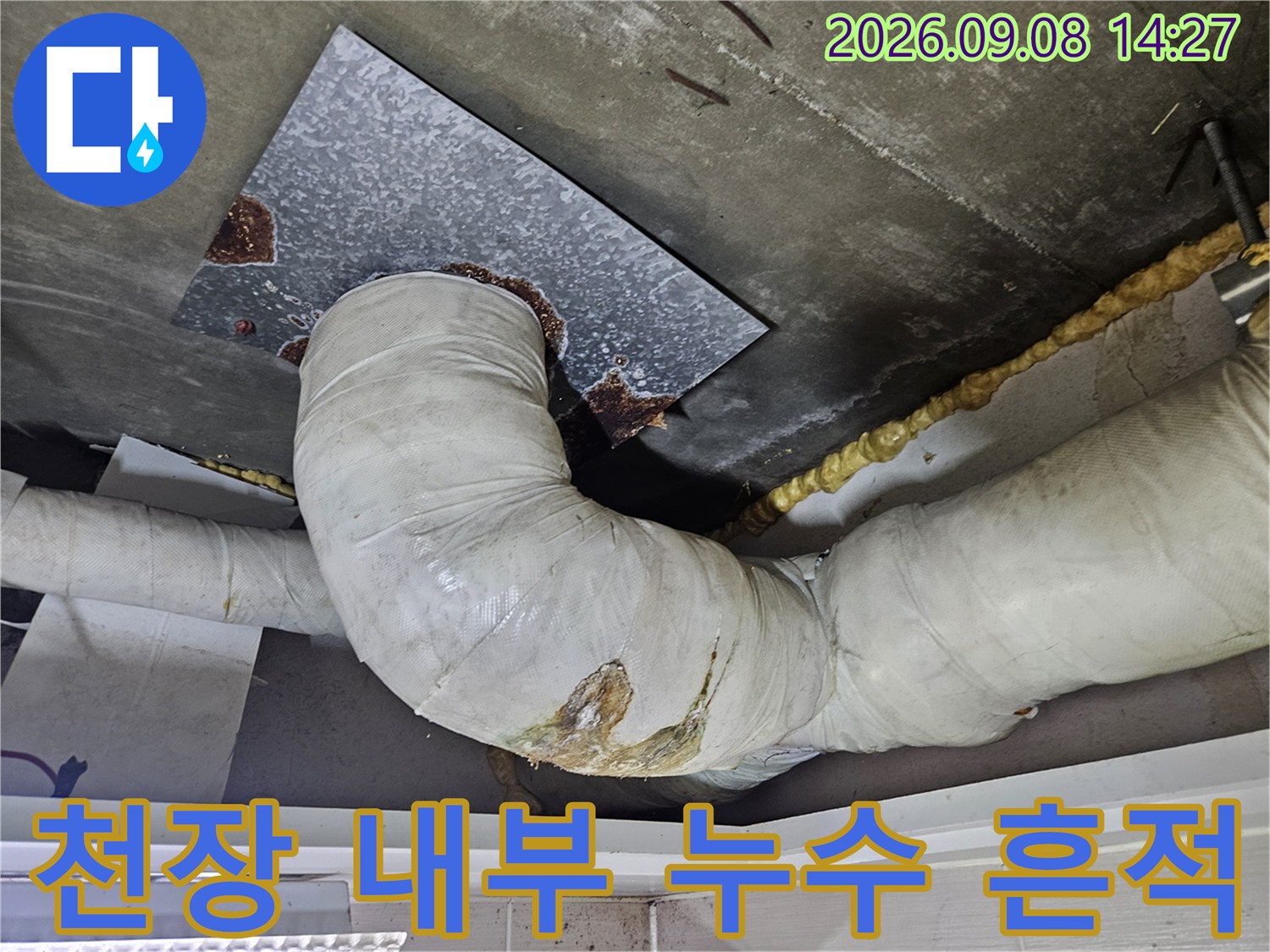 천장 배관 주변의 오염된 슬라브-배관 연결 부위의 누수 자국을 보여줍니다.